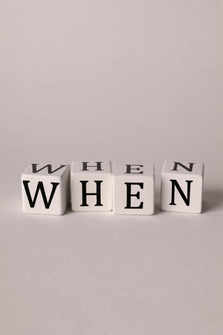 Minimalist close-up of cubes spelling 'When' on a white background.